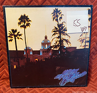 Front cover of Eagles' Hotel California vinyl record showing iconic sunset image and condition grading sticker (55 VG+)