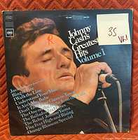 Front cover of Johnny Cash Greatest Hits Volume 1 vinyl record showing album art and grading sticker.