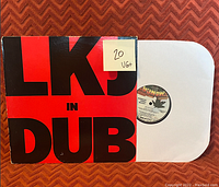 Front cover of vinyl record 'LKJ IN DUB' with partial view of vinyl record inside white protective sleeve.