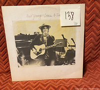 Photo of the front album cover of Neil Young's Comes A Time vinyl record featuring black and white photo of Neil Young with guitar.