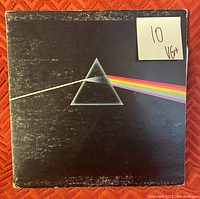 Front cover of Pink Floyd's 'The Dark Side of the Moon' vinyl album with visible wear and a 'VG+' grading sticker on top right corner