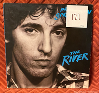 Front cover of vinyl record album The River by Bruce Springsteen, close-up of Springsteen's face in monochrome with blue title text.