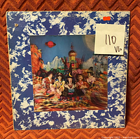 Front cover of The Rolling Stones vinyl album 'Their Satanic Majesties Request' with a blue and white marbled border and psychedelic band artwork in the center, the sleeve shows visible wear and minor damage. Contains grading note 'VG' for media.