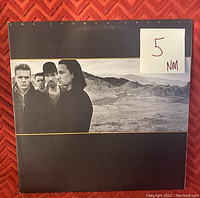Front cover of U2 The Joshua Tree vinyl album with grading sticker '5 NM' visible on the front