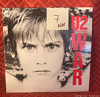 Front of U2 WAR vinyl record album with grade sticker indicating near mint (NM) media condition.