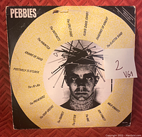 Front cover of Pebbles compilation vinyl record with band names and central black and white portrait with nails in head, marked with condition sticker '2 VG+'