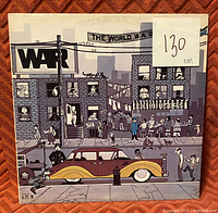Front cover of the vinyl record album "The World Is a Ghetto" by WAR featuring illustrated urban street scene and classic car.