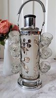 Front view of the entire liquor decanter set including the metal caddy and six attached shot glasses.