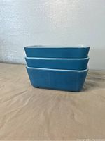 Side view stacked blue Pyrex Fridgies showing scuffs on one dish.
