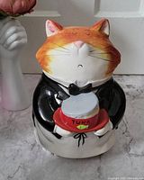 Front view of the cat butler cookie jar showing the cat's orange and white face, black tuxedo, and the tuna can on a red plate.