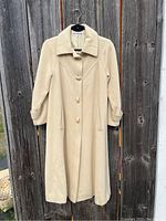 Full view of the vintage ivory jacket hanging showing length, collar, buttons and pockets.