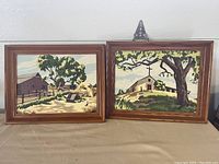 Pair of framed vintage paint by numbers paintings showing barn and church scenes.