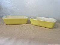Two yellow Pyrex rectangular casserole dishes side by side showing shape and color