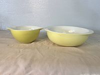 Side profile of two yellow Pyrex bowls showing their nesting design and pouring spouts.