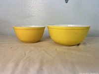Two yellow Pyrex stacking bowls, side by side showing size difference and shape