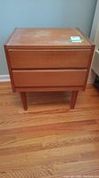 Front view of rectangular bedside table with two drawers and four legs, showing overall condition and design.