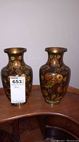 Pair of brass cloisonné vases with floral enamel decoration on a wooden surface showing full front view.
