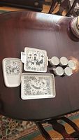 Photo of three trays with Finland pottery black and white graphics and five ceramic cups with handles on table