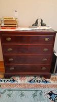 Front view of the four drawer wooden dresser with metal oval drawer pulls and dark polished finish
