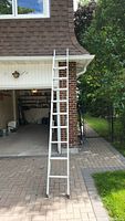 Full view of the metal extension ladder standing upright outside a garage.