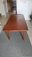 Front perspective of rectangular teak coffee table showing top surface and tapered legs.