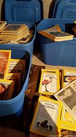 Photo showing multiple blue plastic bins full of National Geographic magazines with classic yellow borders, some stacked and some spread out.
