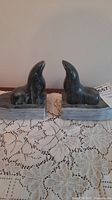 Pair of soapstone seal bookends shown together on lace cloth, providing overall view and scale.
