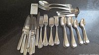 Full overview of Ricci stainless steel flatware set with knives, forks, spoons and serving pieces.