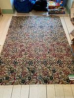 Full view of the Threshold wool area rug laid out on a light wooden floor showing its overall condition and pattern.