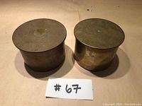 Two brass cylindrical artillery shell cases side by side showing general shape and color.