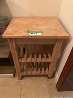 Front view of butcher block island showing butcher block surface and two open slatted wood shelves below