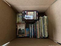 Top-down view of a large box filled with approximately 25 children's books including several Horrible Histories titles.