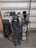 Photo showing three golf bags, golf clubs, two tennis rackets, rollerblades, and shoes.