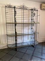 Full front view of baker's rack showing overall structure, three glass shelves, bottom wire shelf and decorative scrollwork