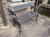 Full left-front view of cast iron bench showing backrest and seat pattern.