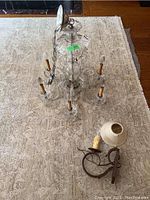 Top angle full view of Murano style glass chandelier and iron wall sconce lamp with shade on carpeted floor.