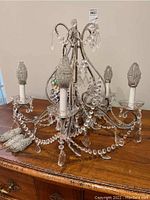 Full view of chandelier on wooden surface showing five arms, crystal bead strands and beaded bulb covers