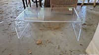 Front view of clear Lucite coffee table on concrete floor