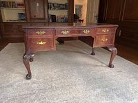 Full front view of the desk showing all four drawers and carved legs