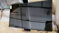 Front view of LG 49-inch LED TV face with remote placed beneath the screen.