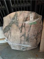 Pink and black marble table top wrapped in plastic, showing the marble pattern and bevelled edges.