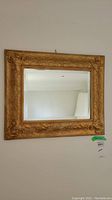 Full view of the vintage gold framed rectangular mirror hanging on a wall, showing overall condition and size.