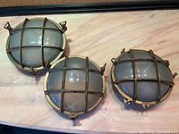 Three vintage brass and glass nautical lights with frosted domed glass, metal cross grid protective grilles, and 3 mounting brackets