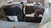 Front view of both cube ottomans side by side showing patchwork hide pattern