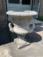 Front-side angle view showing planter's overall shape, decorative carved design, and visible cracks.