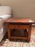 Full view of the side table next to a light-colored sofa, showing the drawer with metal ring pull and overall structure.