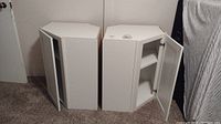 Photo showing both white corner cabinets with doors open revealing interior shelves.