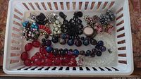 Assorted beaded necklaces and faux pearl bracelets in plastic basket