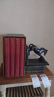 Full view of four Harper Encyclopedia of Science volumes with black horse bookend on a wooden table, alongside other vintage books and two sets of horse bookends.