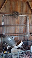 Galvanized gate leaning against a wooden wall with various items nearby in silo.